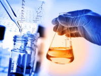Flask in scientist hand with laboratory background